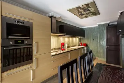 a kitchen with wooden cabinets and a bar with chairs at The Sapphire Apartment with Private Swimming Pool & Hot Tub - Hivernage Quarter - By Goldex Marrakech in Marrakech