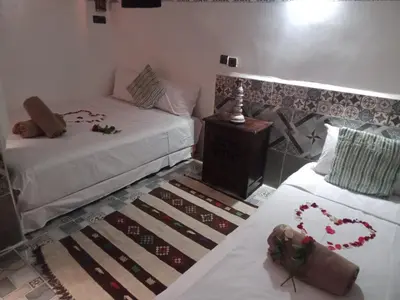 a living room with two beds and a table with at Riad Wink in Marrakech