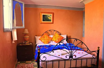 a bedroom with a bed with orange walls at Riad Wink in Marrakech