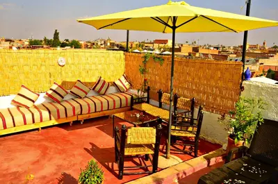 a patio with a couch and a table and an umbrella at Riad Wink in Marrakech