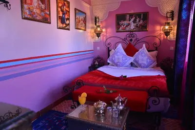 a bedroom with a red bed and a table at Riad bleu du Sud in Marrakech