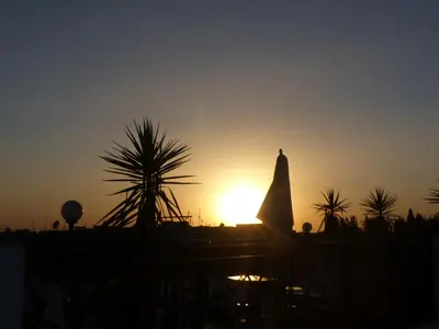 a sun setting in the distance with a building in the background at Riad Tchina in Marrakech
