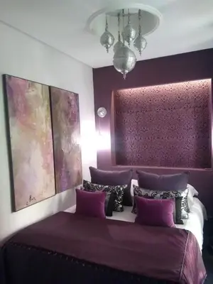 a bedroom with purple walls and a bed with purple pillows at Riad Tchina in Marrakech