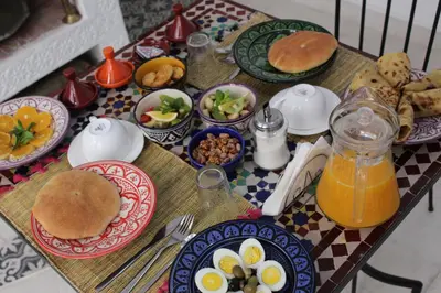 a table topped with plates of breakfast food and orange juice at Riad El Arco ROOFTOP POOL & Spa in Marrakech