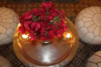 a vase of red flowers on a table with candles at Riad El Arco ROOFTOP POOL & Spa in Marrakech
