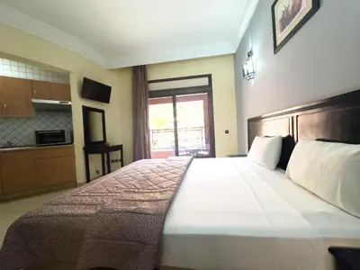 a bedroom with a large bed and a kitchen at Mogador Menzah Appart Hôtel in Marrakech