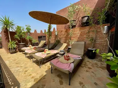 a group of chairs and an umbrella on a patio at Riad La Porte Rouge By La Siredrah in Marrakech