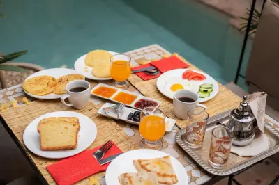 a table topped with plates of breakfast food and orange juice at Riad La Porte Rouge By La Siredrah in Marrakech