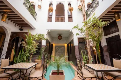 a courtyard in a building with tables and plants at Riad La Porte Rouge By La Siredrah in Marrakech