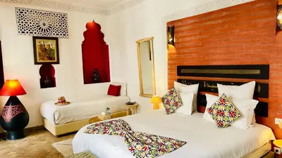 a bedroom with two beds and a red brick wall at Riad La Porte Rouge By La Siredrah in Marrakech