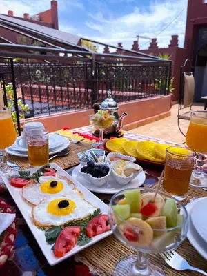 a table with breakfast foods and drinks on a balcony at Riad La Porte Rouge By La Siredrah in Marrakech
