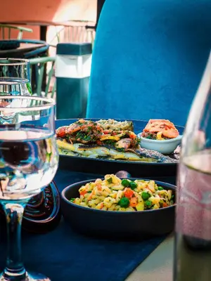 a table with plates of food and a glass of wine at Grand Mogador Menara & Spa in Marrakech