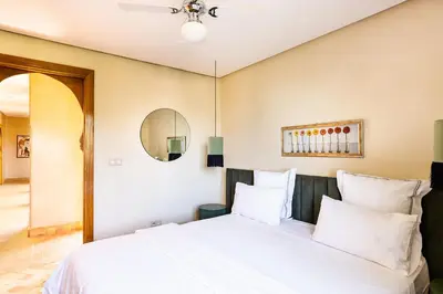 a bedroom with a bed with white sheets and a mirror at Villa de Luxe avec Piscine Privée et Golf in Marrakech