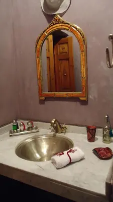 a bathroom sink with a mirror and towels on it at Riad Tahar Oasis in Marrakech