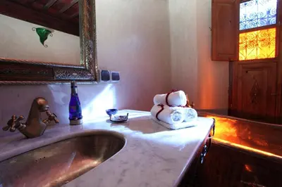 a bathroom with a sink and a mirror and towels at Riad Tahar Oasis in Marrakech