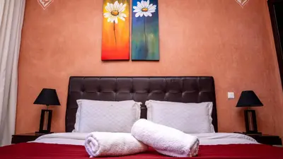 a bedroom with a bed with two paintings on the wall at Appartements Marrakech Garden in Marrakech