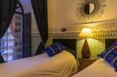 a bedroom with two beds and a lamp and a window at Riad Sidi Omar in Marrakech