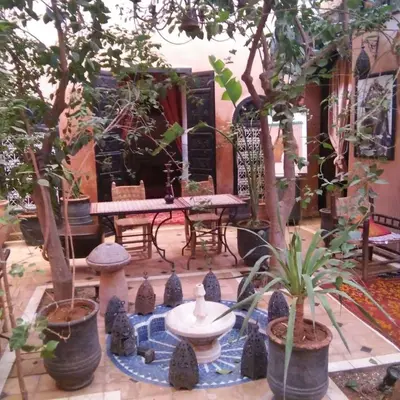 a courtyard with trees and a table and a fountain at Riad Sidi Omar in Marrakech