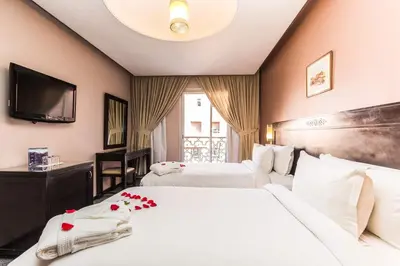 a hotel room with two beds and a flat screen tv at Hotel Almas in Marrakech