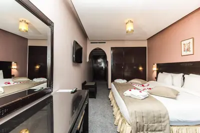 a hotel room with two beds and a mirror at Hotel Almas in Marrakech