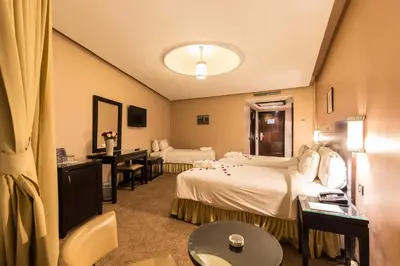 a hotel room with two beds and a desk at Hotel Almas in Marrakech