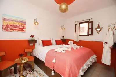 a bedroom with two beds with red walls and a window at Riad Heklek in Marrakech