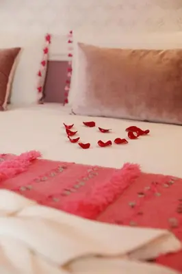 a pile of red rose petals on a bed at Riad Heklek in Marrakech