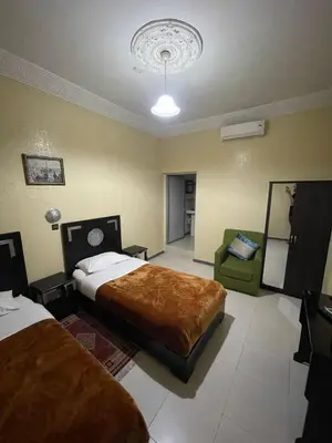 a hotel room with two beds and a chair at Hôtel Narjisse in Marrakech