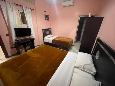a small bedroom with two beds and a television at Hôtel Narjisse in Marrakech
