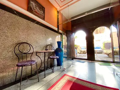 a room with two chairs and a table and a vase at Hôtel Narjisse in Marrakech