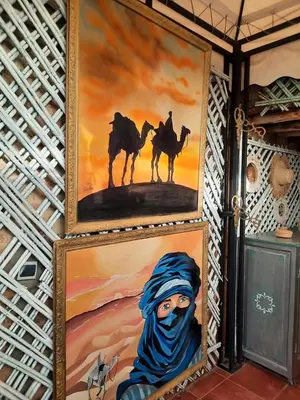 a group of paintings on a wall with camels at Riad 1001 couleurs in Marrakech