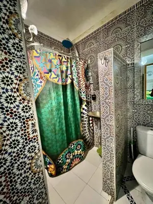 a bathroom with a shower with a green shower curtain at Riad 1001 couleurs in Marrakech