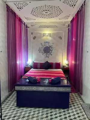 a bedroom with a large bed with pink curtains at Riad 1001 couleurs in Marrakech