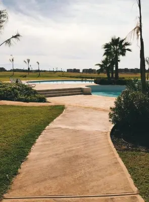 a pathway leading to a swimming pool with palm trees at Prestigia golf pour les familles in Marrakech