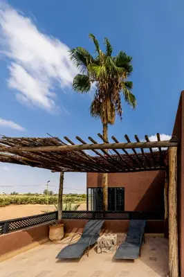 a building with a palm tree and two chairs at Fellah Hotel in Marrakech