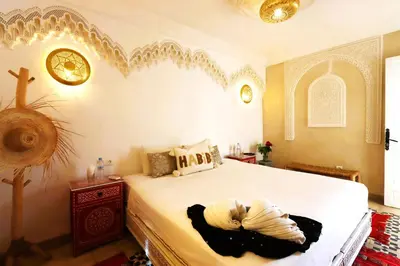 a bedroom with a large white bed with a clock on the wall at Riad Makech in Marrakech