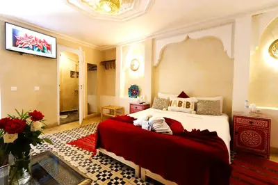 a bedroom with a large bed with a red blanket at Riad Makech in Marrakech