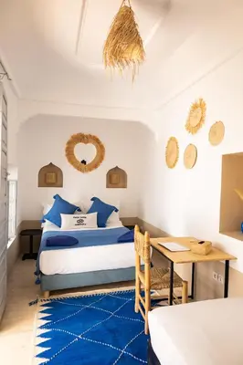 a bedroom with a bed and a table with a blue rug at Riad El Jadide in Marrakech