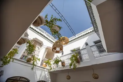 a white building with potted plants on a balcony at Riad El Jadide in Marrakech