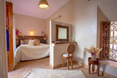 a bedroom with a bed with a mirror and a chair at Riad Darino Marrakech Heritage in Marrakech
