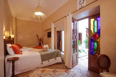 a bedroom with a bed and a door with stained glass at Riad Darino Marrakech Heritage in Marrakech