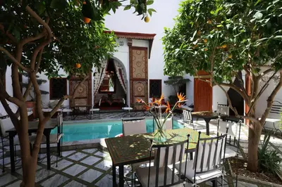 a patio with a table and chairs next to a pool at Riad Zineb in Marrakech
