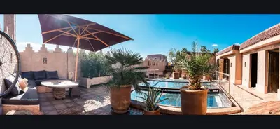 a patio with a swimming pool and an umbrella at Dar d'Art in Marrakech