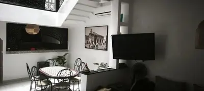 a living room with a tv and a table and chairs at Riad Naim in Marrakech