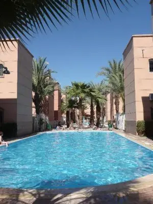 a large swimming pool with blue water and palm trees at Riad Naim in Marrakech