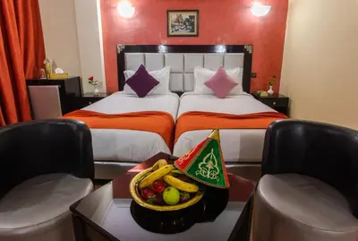 a hotel room with two beds and a basket of fruit at Hotel Meriem Marrakech in Marrakech