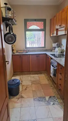 a kitchen with wooden cabinets and a tile floor at Palmeraie village 2 , les jardins de la palmeraie 2 in Marrakech