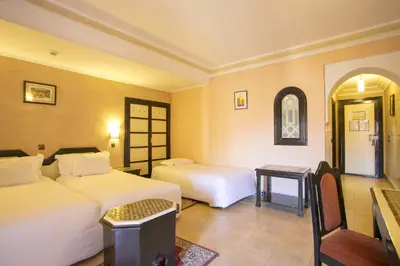 a hotel room with two beds and a table at Diwane Hotel & Spa Marrakech in Marrakech