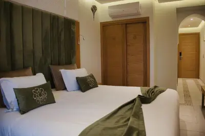 a bedroom with a bed with white sheets and green pillows at Diwane Hotel & Spa Marrakech in Marrakech