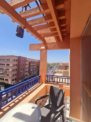 a balcony with two chairs and a table on a building at Hotel Tachfine in Marrakech